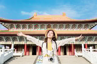 A young lady on a rucksack stands in front of a traditional Chinese temple A young lady on a rucksack stands in front of a traditional Chinese temple