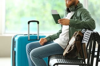handsome man with passport sitting on chair in hall of airport handsome man with passport sitting on chair in hall of airport