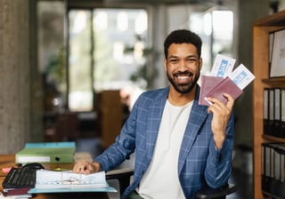 young happy man holding plane tickets in office young happy man holding plane tickets in office