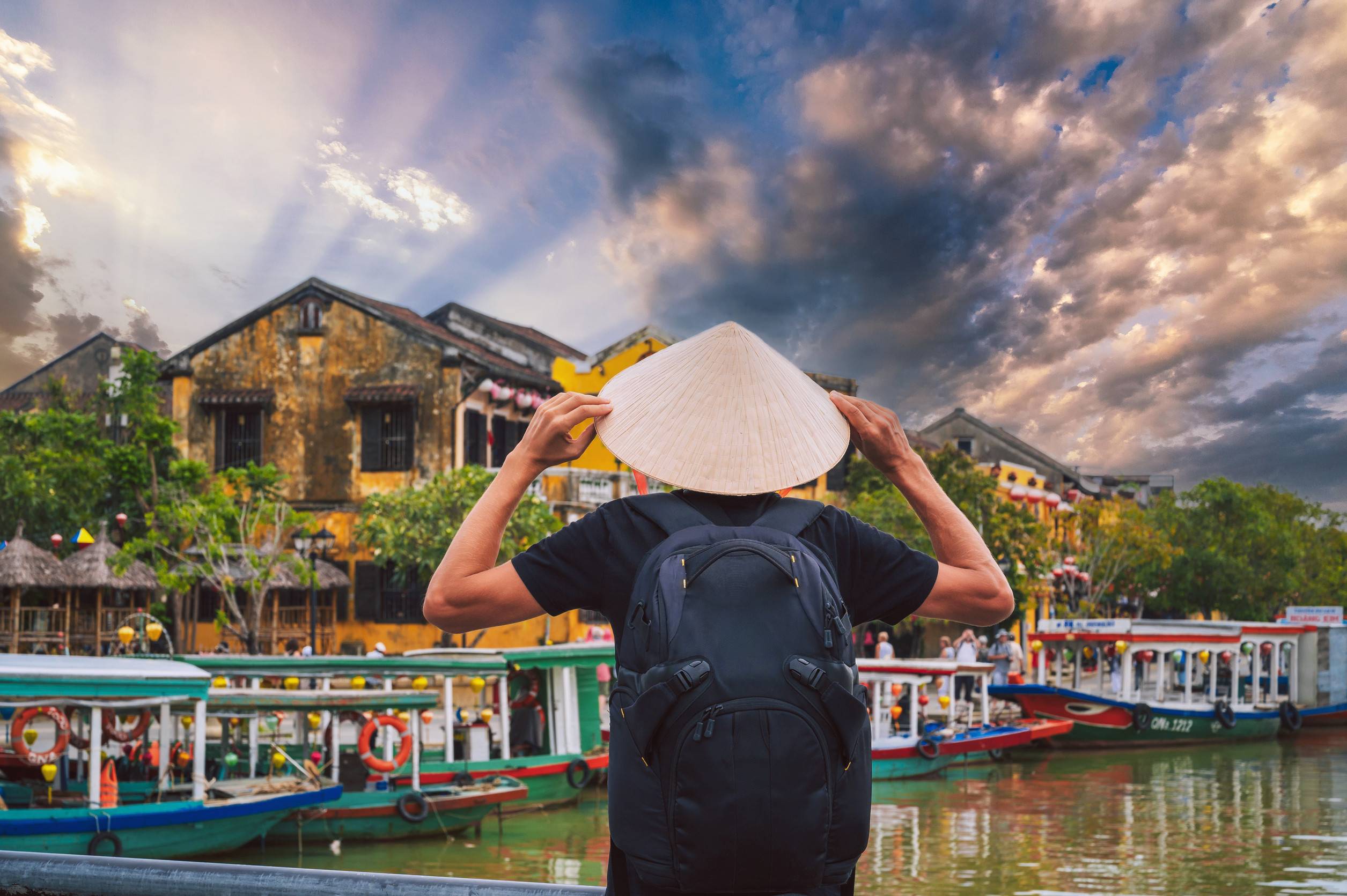Back of male tourist traveler in Vietnamese hat on a bridge in old town in Hoi An in Vietnam in Asia Back of male tourist traveler in Vietnamese hat on a bridge in old town in Hoi An in Vietnam in Asia