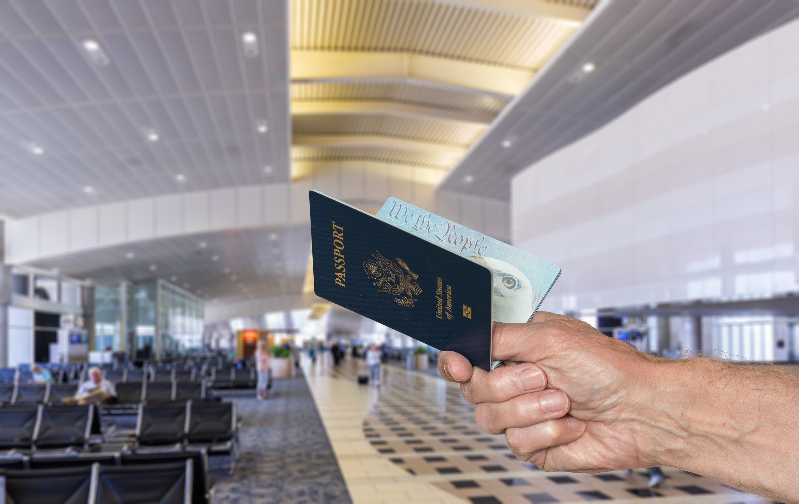 Senior caucasian arm holding an open USA passport to show to official in airport terminal Senior caucasian arm holding an open USA passport to show to official in airport terminal