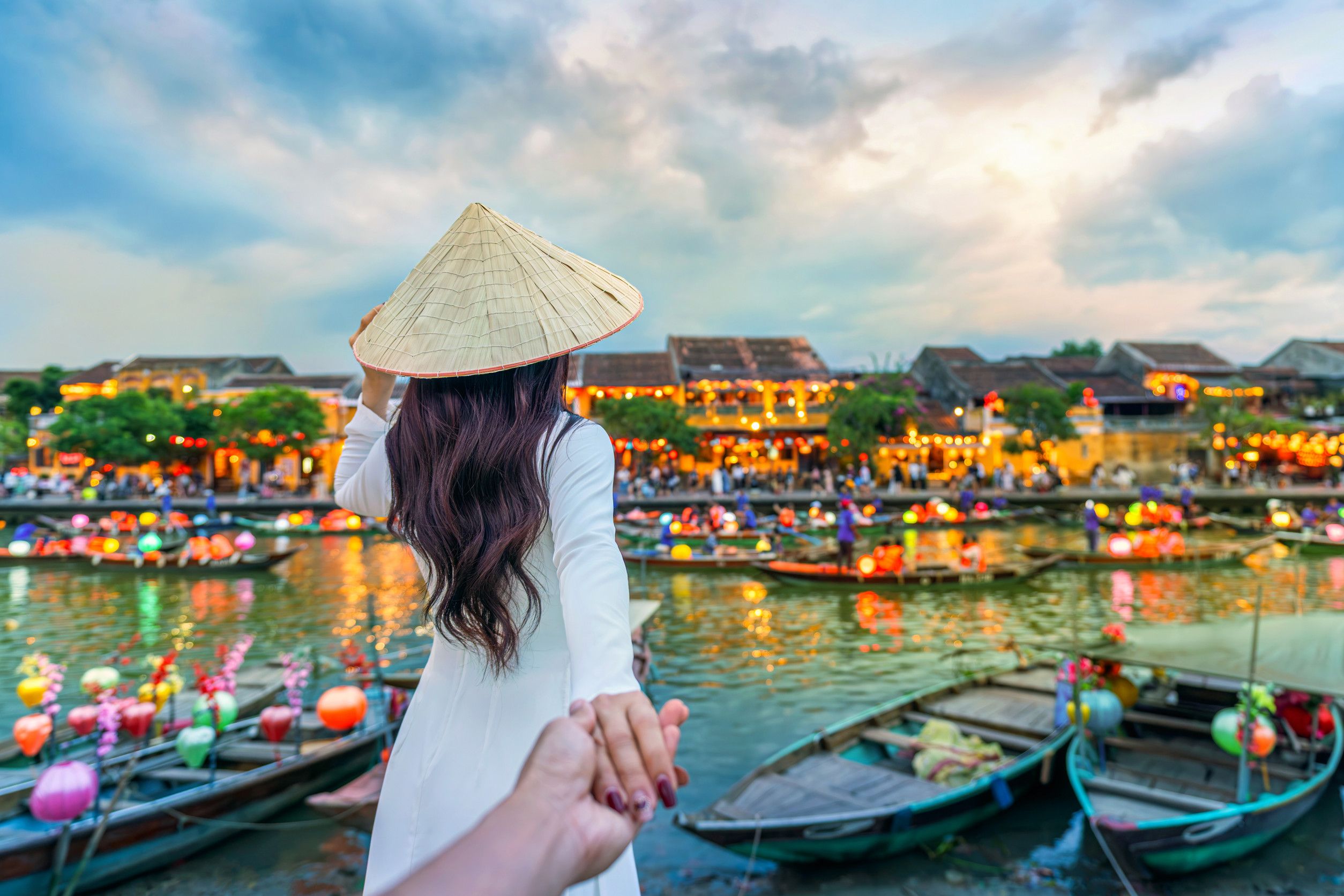 Women tourist holding man's hand and leading him to Hoi An ancient town, Hoi An city in Vietnam Women tourist holding man's hand and leading him to Hoi An ancient town, Hoi An city in Vietnam